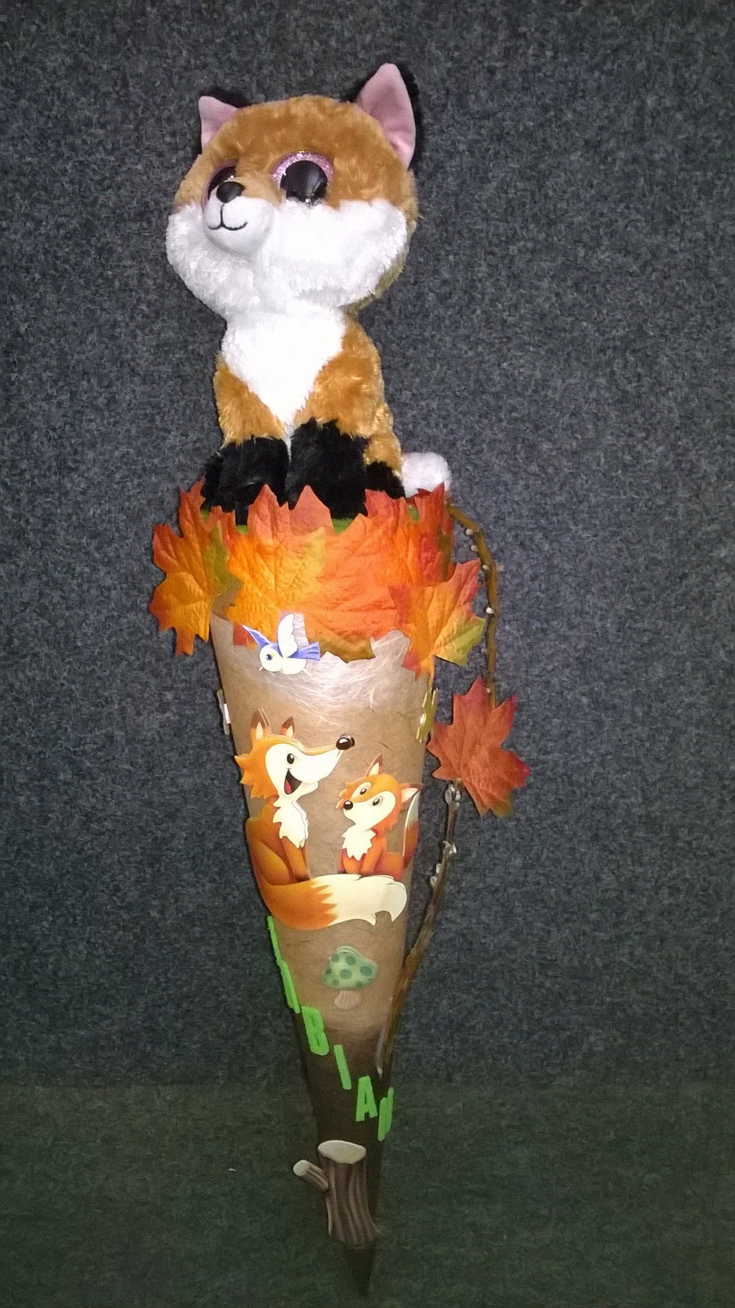 Ein ausgestopfter Fuchs sitzt auf einem Kegel mit Blättern.