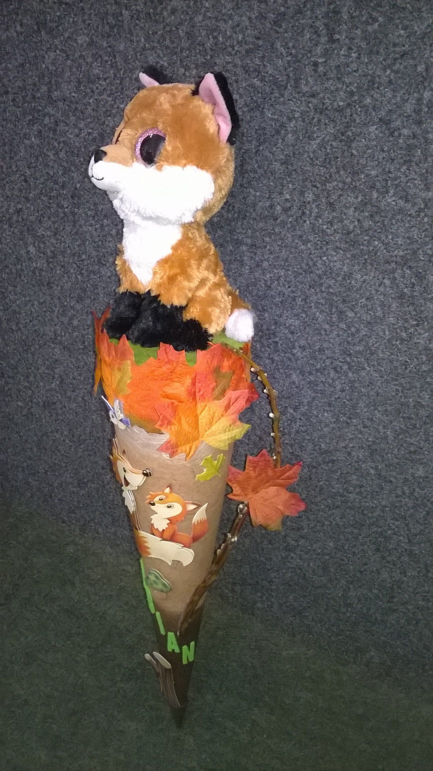 Ein ausgestopfter Fuchs sitzt in einem mit Blättern gefüllten Kegel.