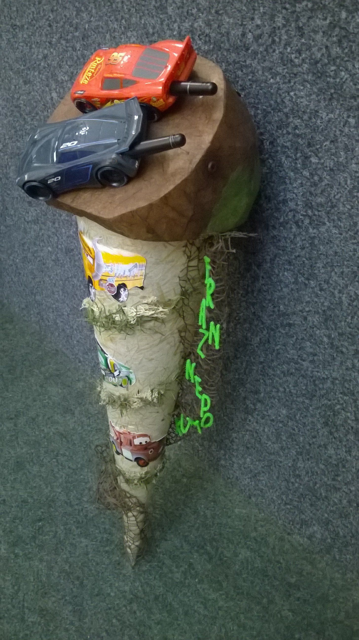 Drei Spielzeugautos stehen auf einem Holzstumpf.