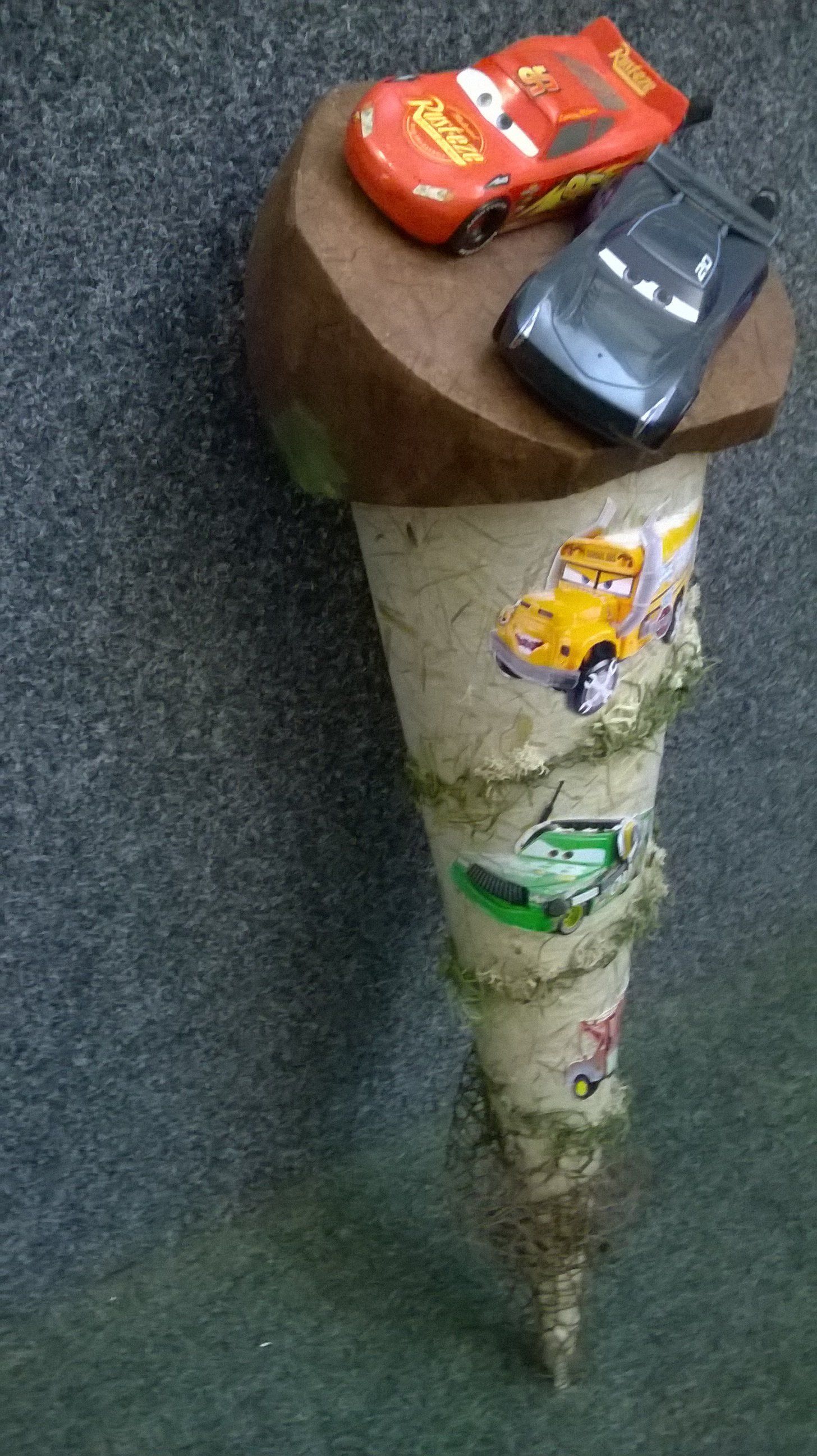 Zwei Spielzeugautos sitzen auf einem Holzkegel.