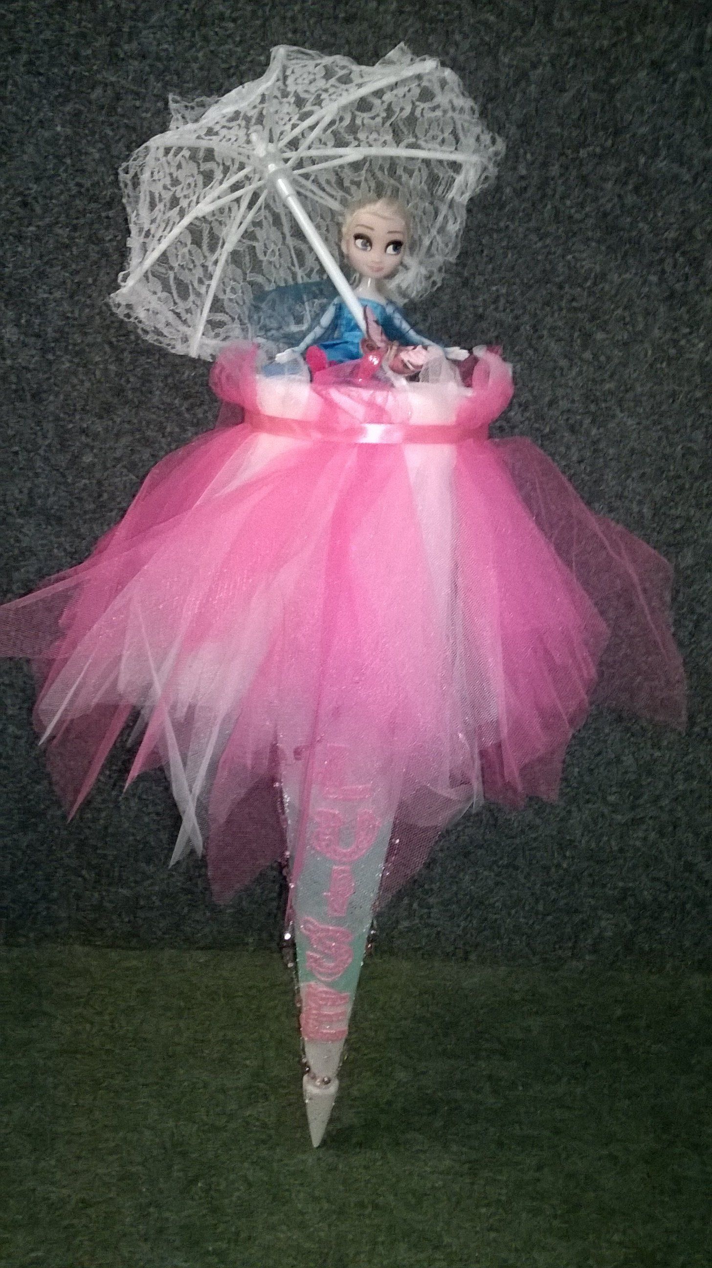 Eine Puppe in einem rosa Tutu hält einen Regenschirm.