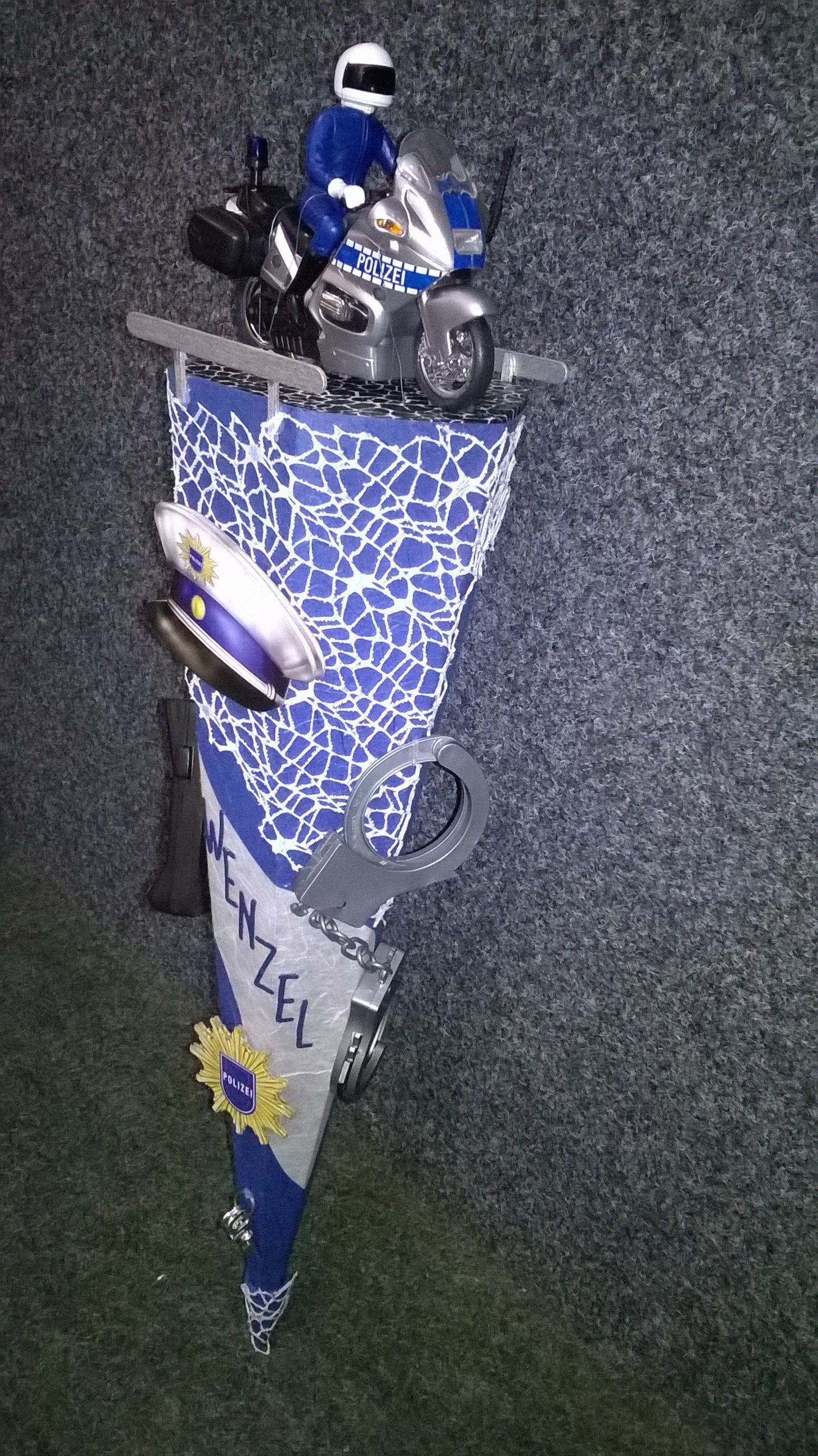 Ein blau-weißer Kegel mit einem Spielzeug-Polizisten auf einem Motorrad.