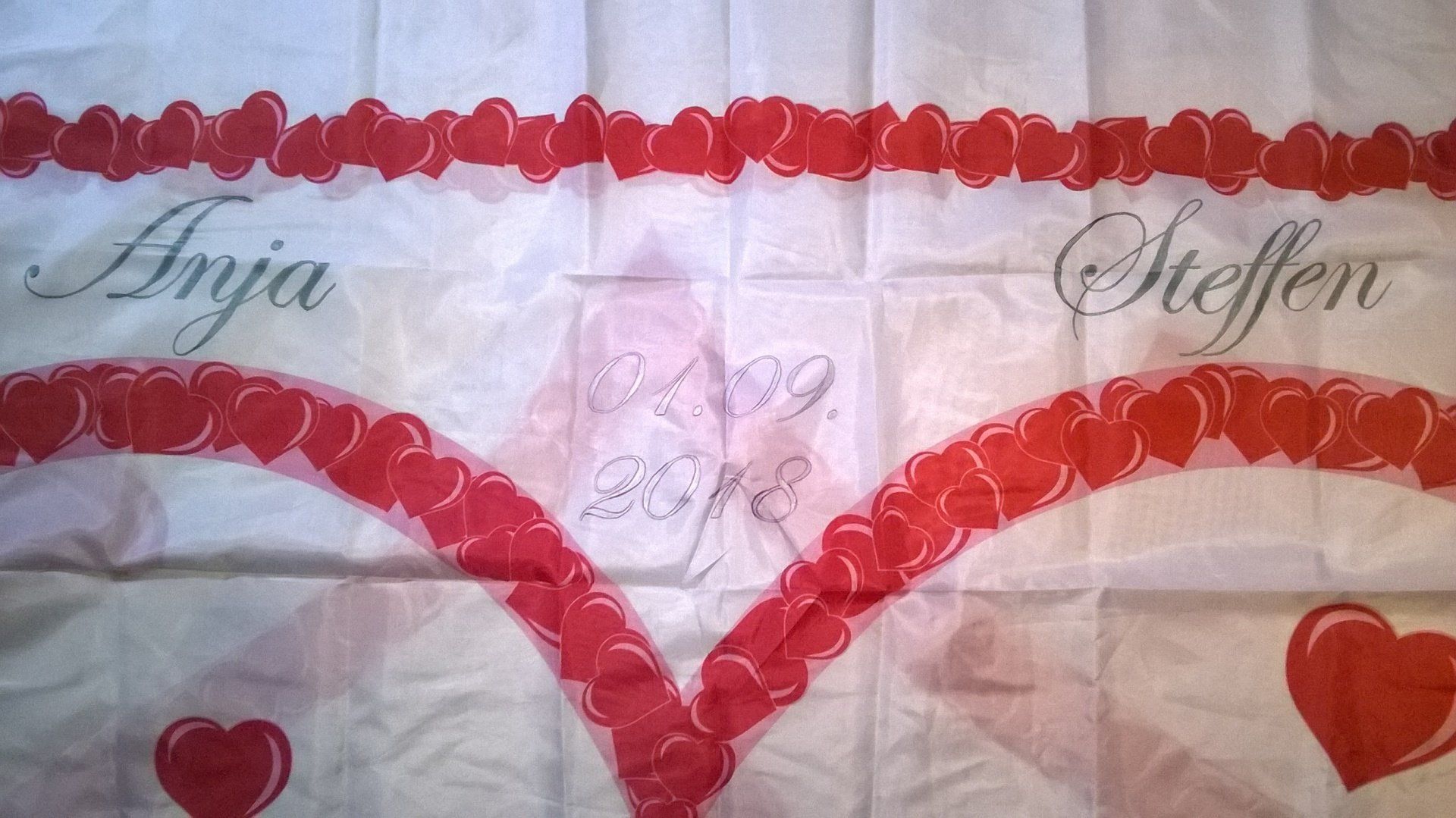 Ein weißes Tuch mit roten Herzen und den Namen Anja und Steffen darauf