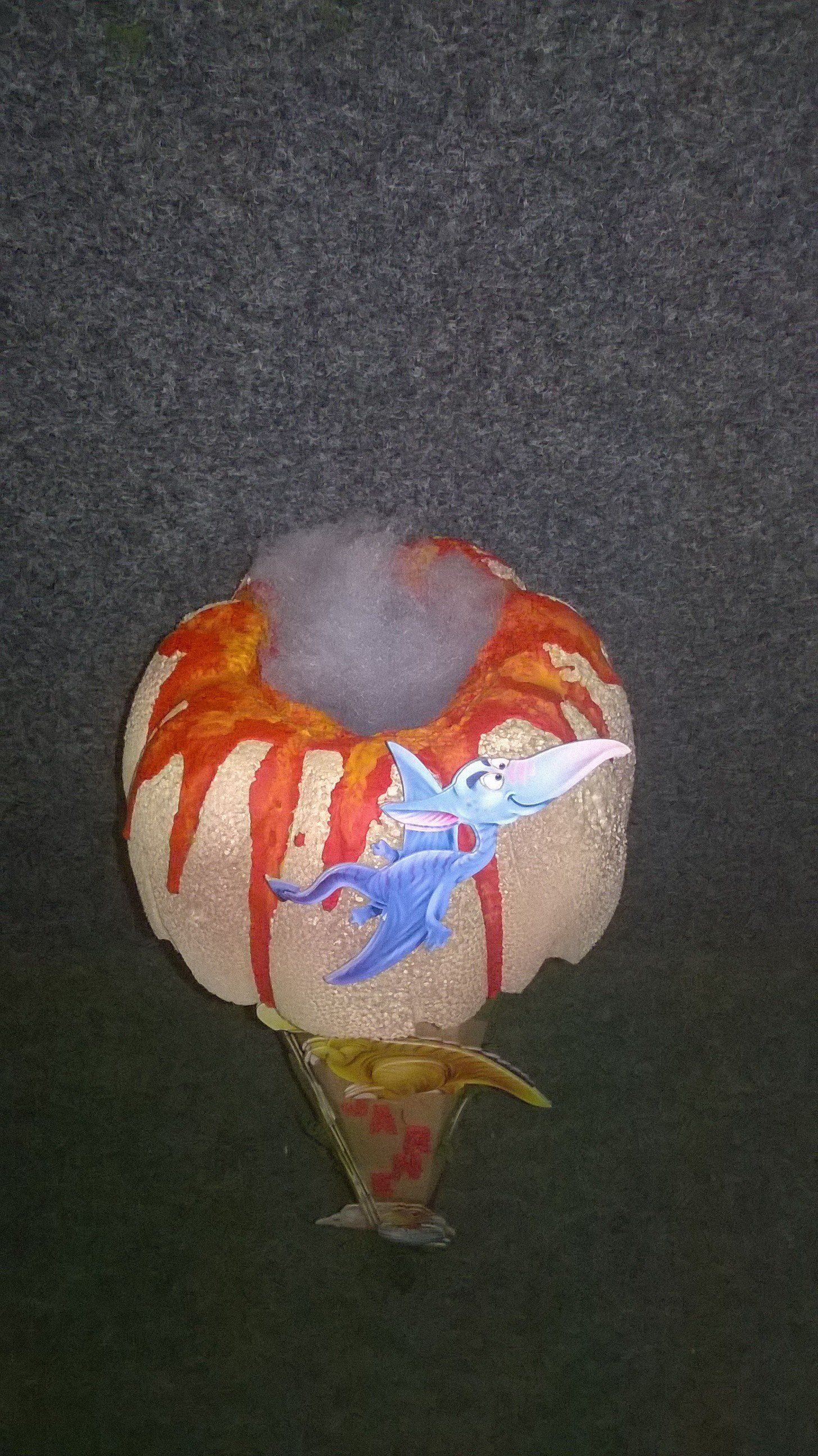 Auf einem Tisch steht ein Spielzeugvulkan mit Dinosauriern darauf.