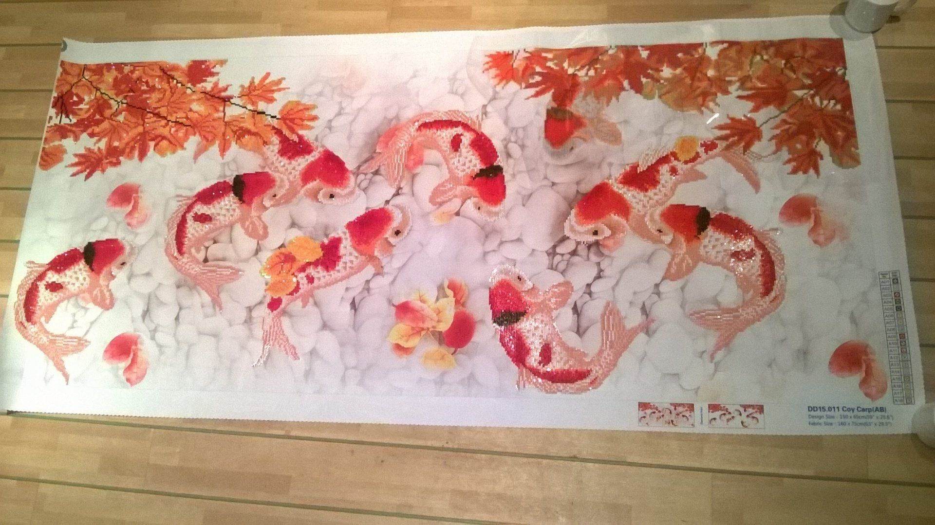 Ein Gemälde von Fischen und Blättern auf einem Holzboden