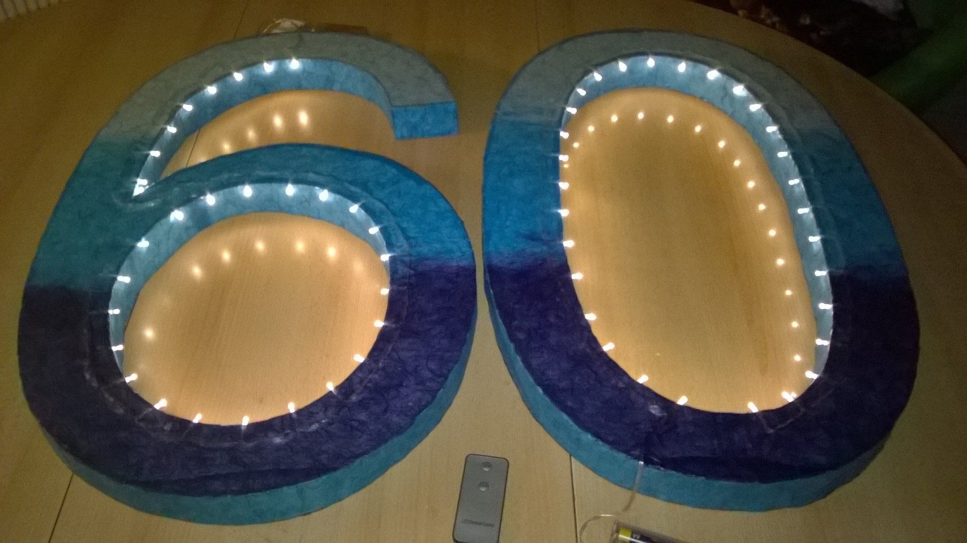 Eine blaue und violette Zahl 60 mit Lichtern darum