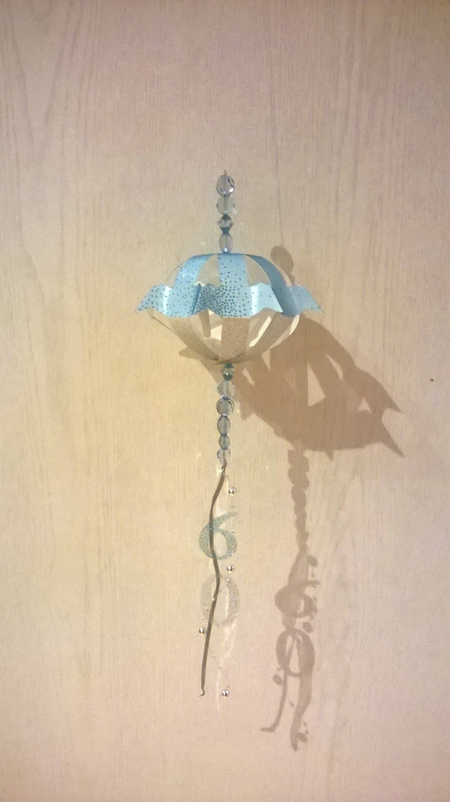 Ein blau-weißer Luftballon hängt an einer Schnur an einer Wand.