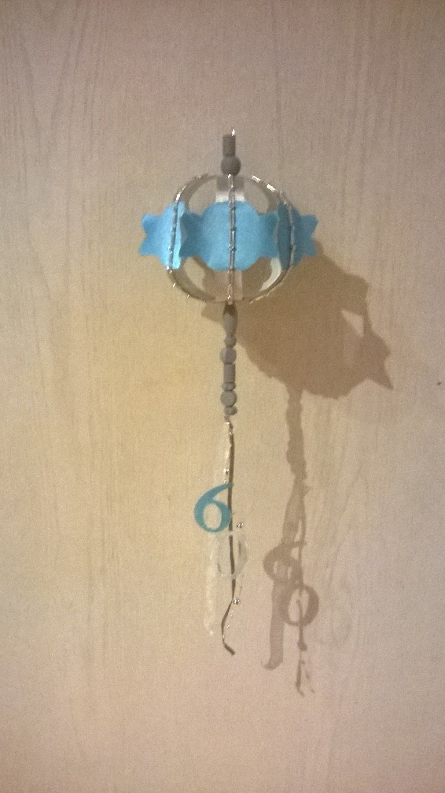 An einem Haken an der Wand hängt ein blaues Windspiel.