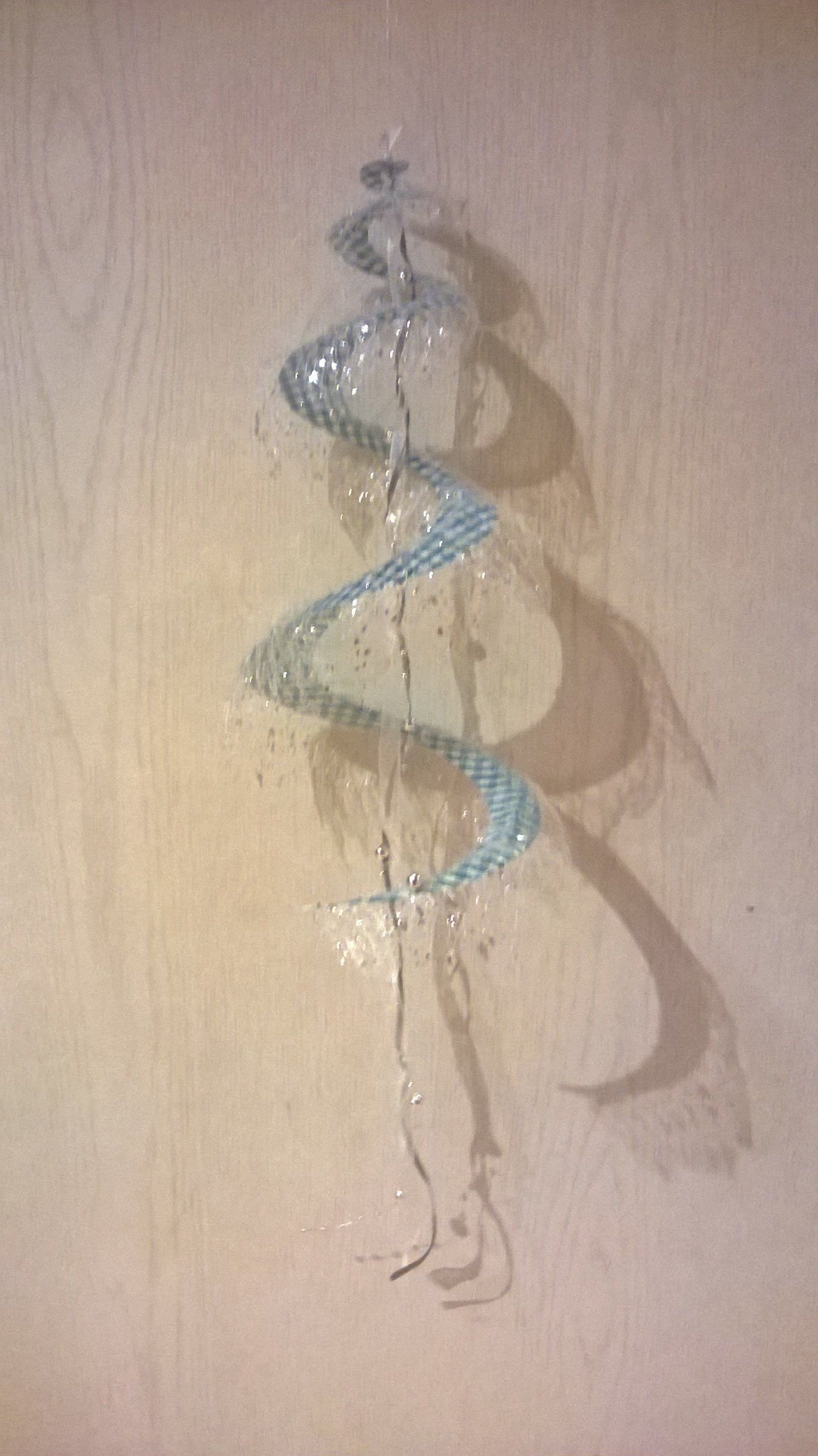 Ein blaues Band hängt an einer Schnur an einer Wand.