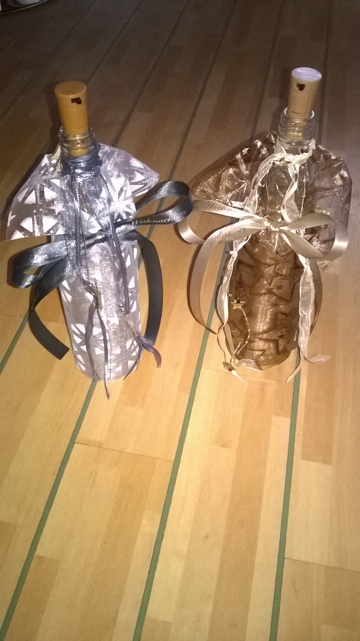 Zwei Flaschen Wein stehen auf einem Holzboden.