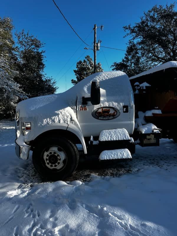 White semi-truck buried in snow on a snowy road under a clear blue sky White semi-truck buried in snow on a snowy road under a clear blue sky