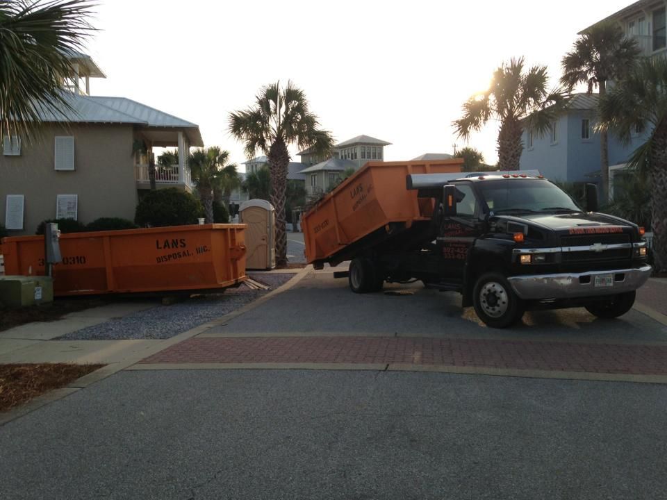 Black truck with orange dumpster bins blocking a gated driveway in a residential neighborhood Black truck with orange dumpster bins blocking a gated driveway in a residential neighborhood