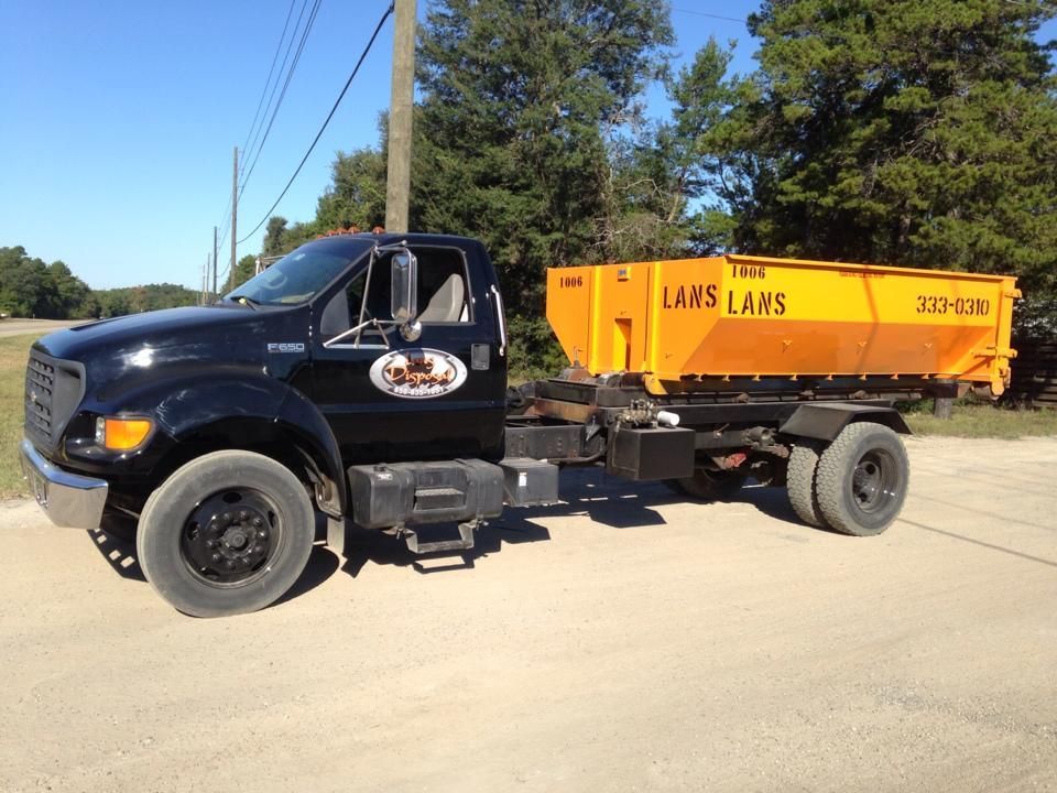 Black dump truck with orange Lams container parked on a sunny roadside near trees Black dump truck with orange Lams container parked on a sunny roadside near trees