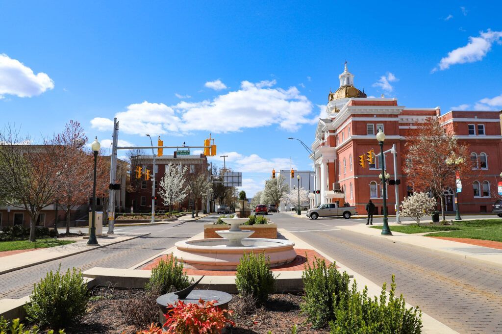 Downtown street scene with a brick road, a fountain, and a red brick building with a gold dome.