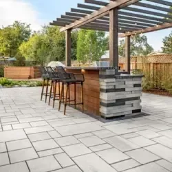 A patio with a bar and stools under a pergola.