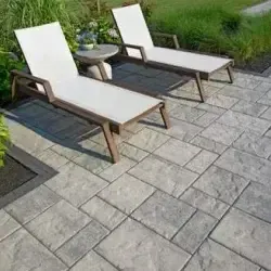 Two lounge chairs are sitting on a patio next to a table.