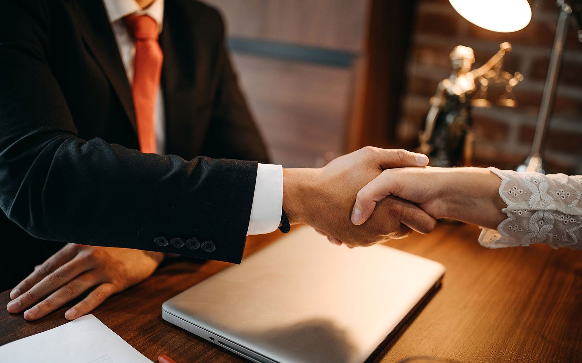 A man in a suit and tie is shaking hands with a woman.