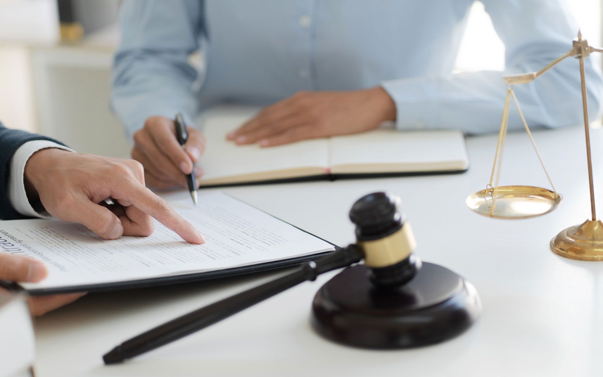 A man and a woman are sitting at a table with a gavel and scales of justice.