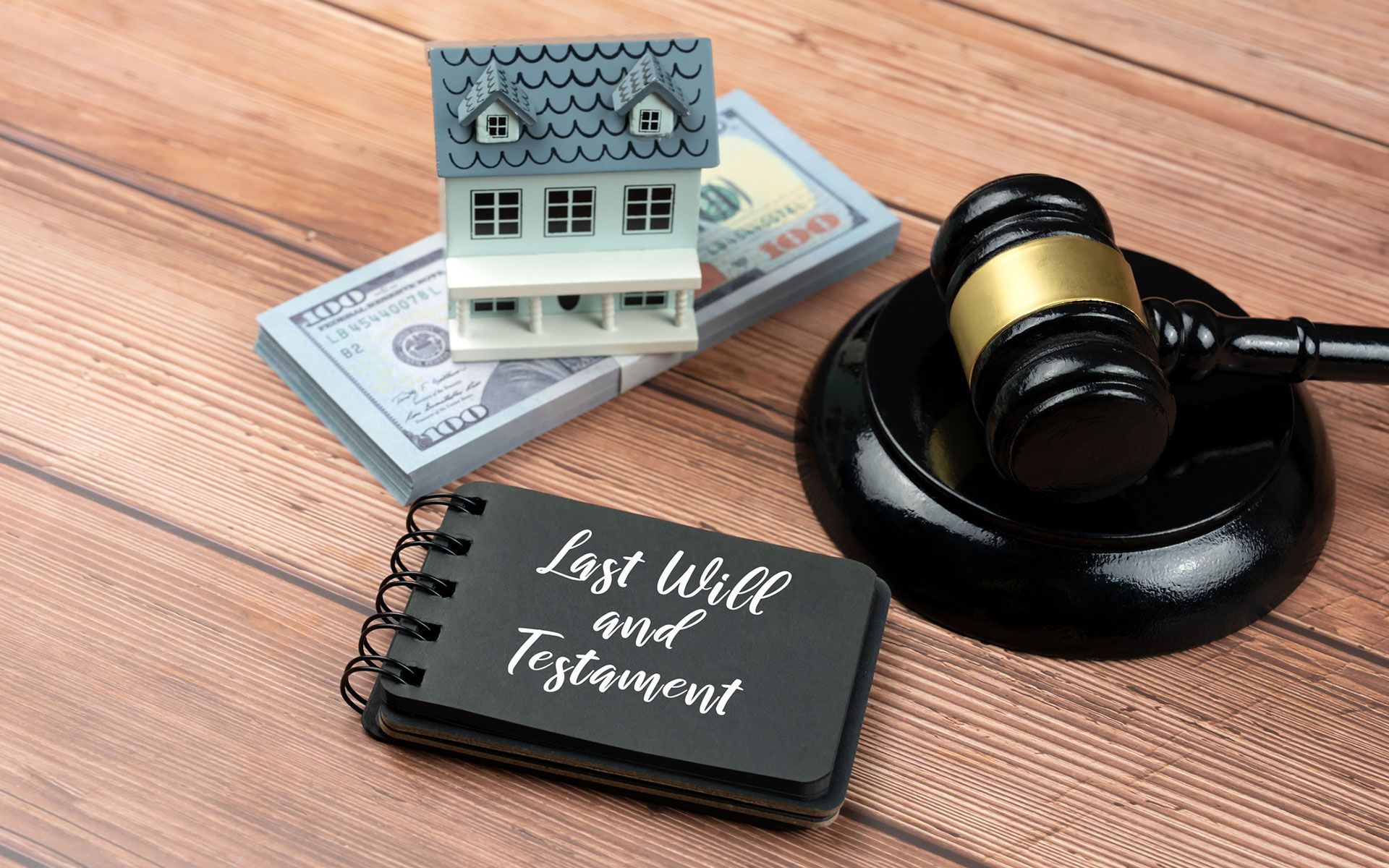 A judge 's gavel is sitting on a wooden table next to a book about last will and testament.