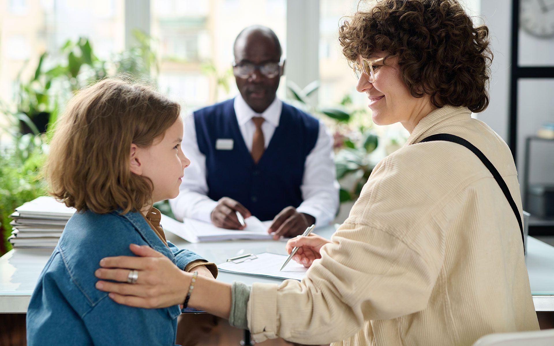 A woman is hugging a little girl while sitting at a table.