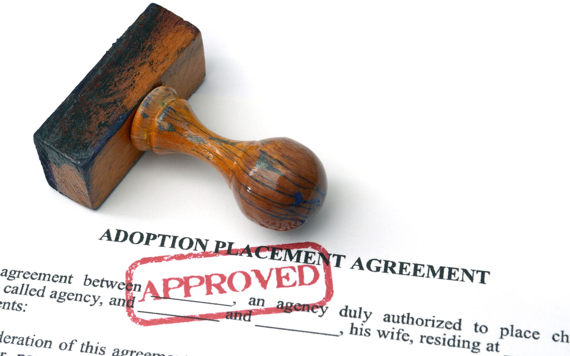 A wooden stamp on top of an adoption placement agreement