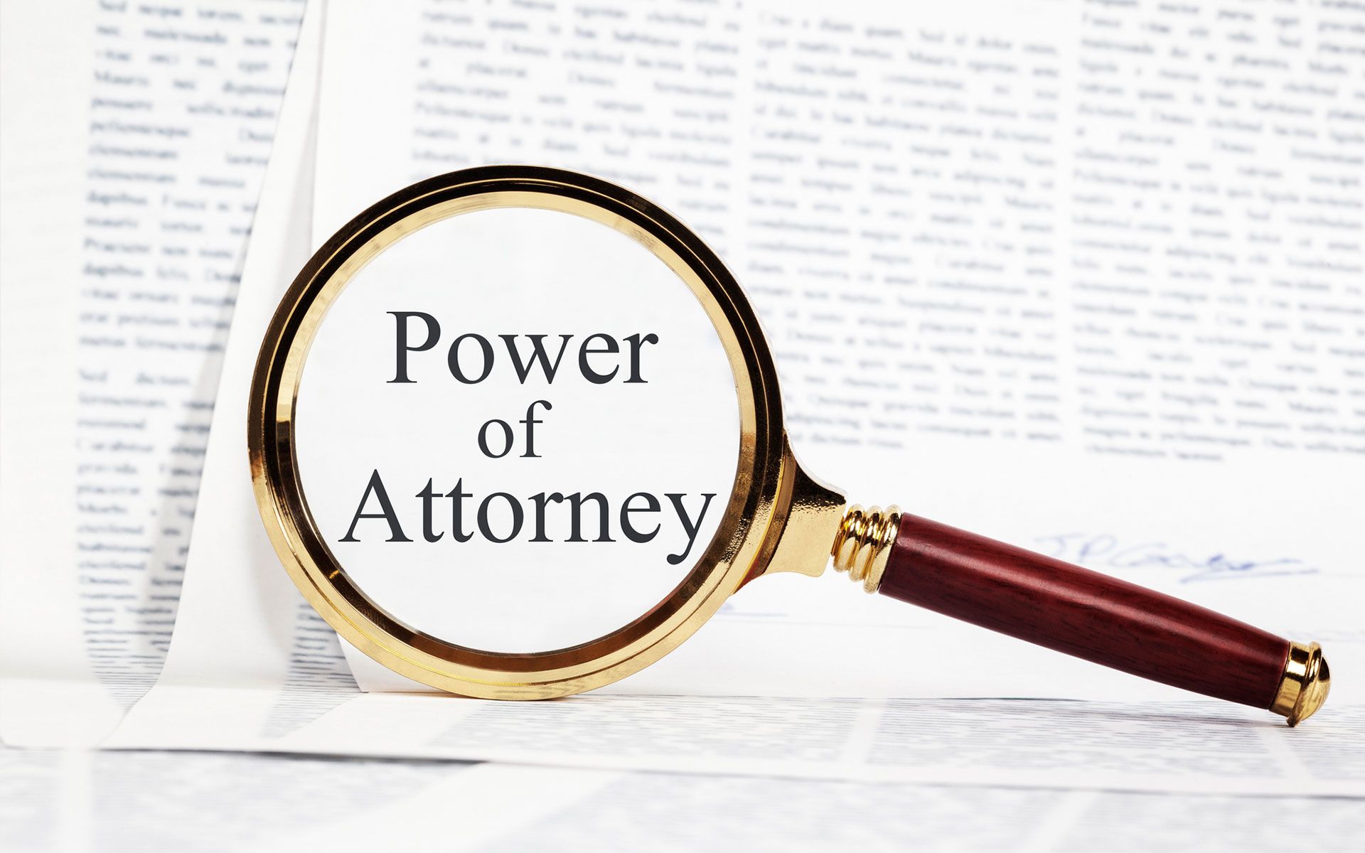 A magnifying glass is sitting on top of a piece of paper that says power of attorney.