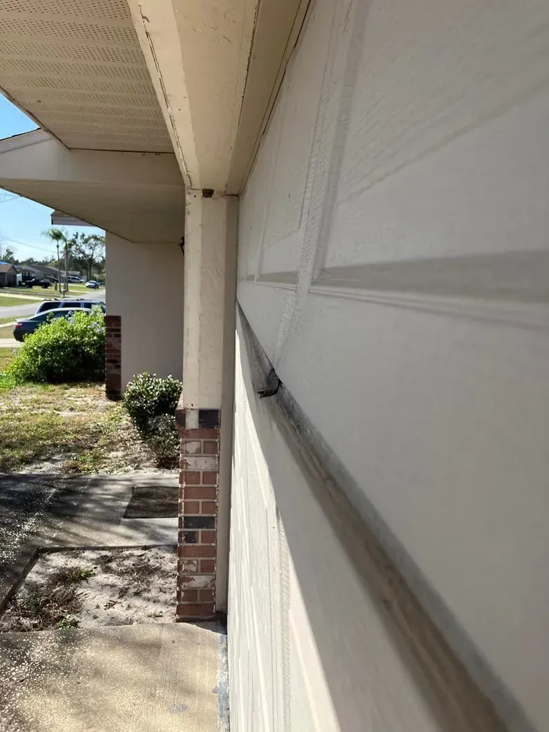 Exterior view of a house. White siding and a beige covered porch. Brick column and a grassy yard.