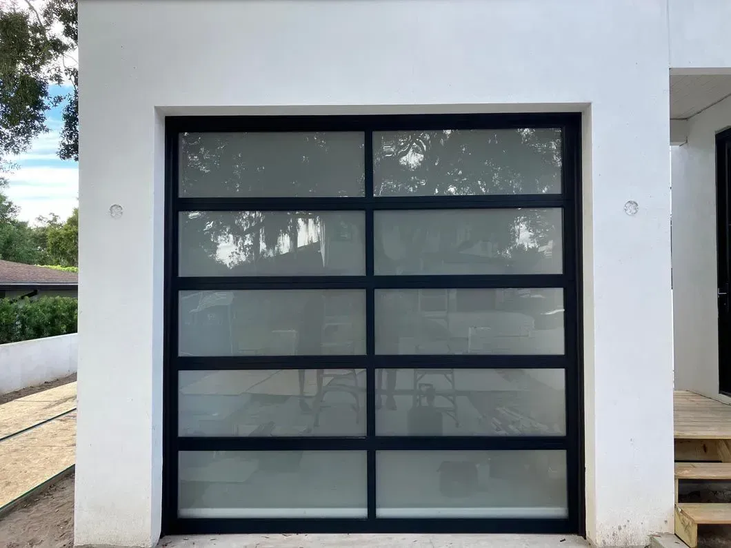 Black-framed garage door with frosted glass panels set in a white exterior.