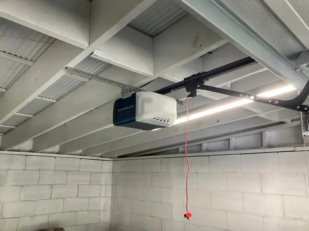commercial garage door services apopka fl Garage ceiling with white beams and an automatic door opener. Red emergency release cord hangs down.