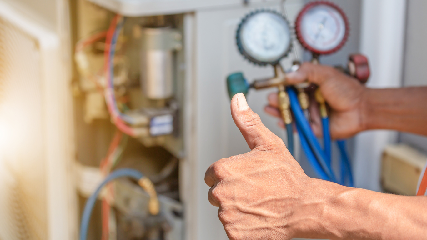 Person with tools giving thumbs up while working on an AC unit.