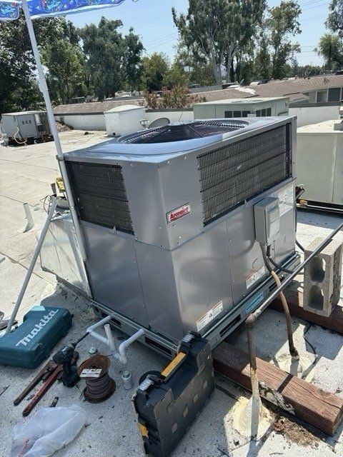 Rooftop air conditioning unit with tools, Coleman brand, sunny day.
