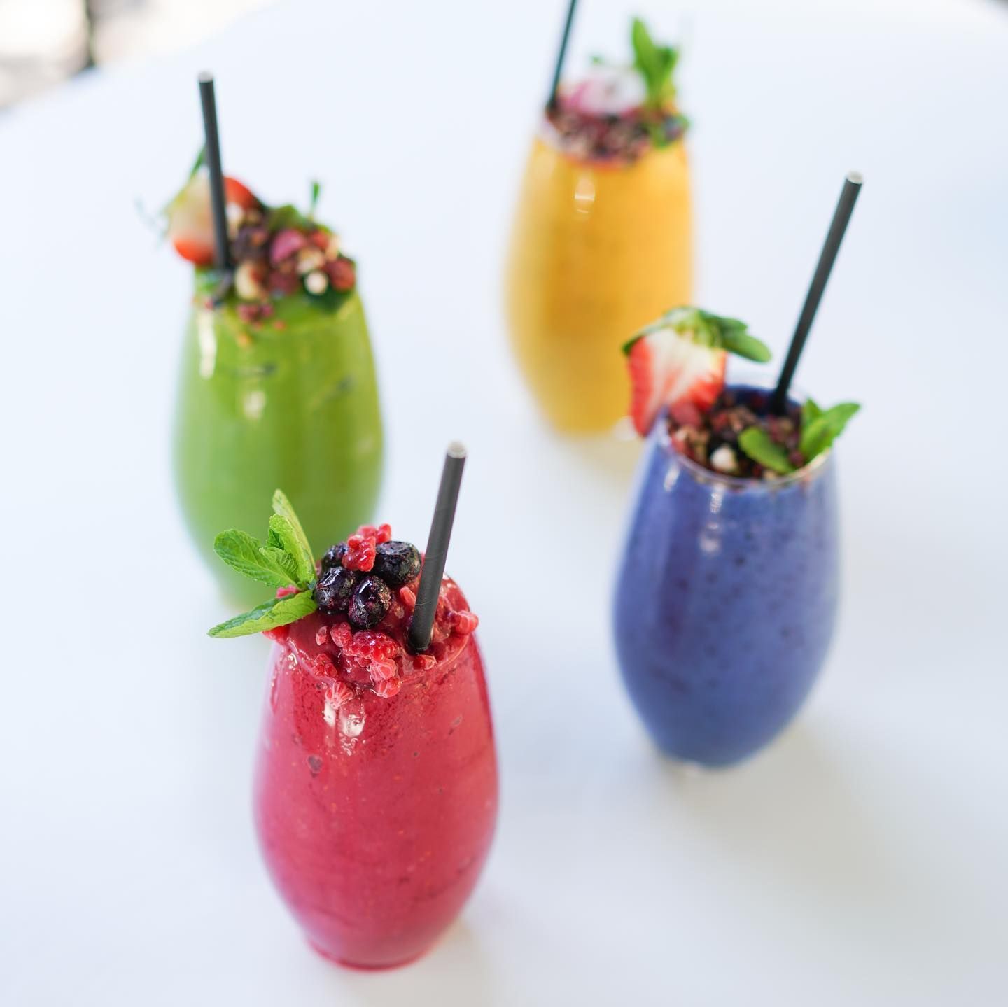 Four Different Colored Smoothies With Straws on a Table — The Pass Cafe in Byron Bay, NSW