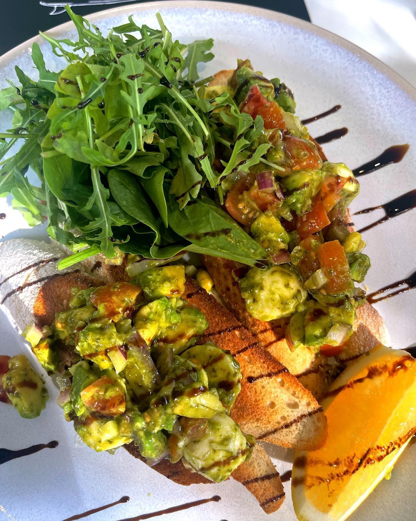 A White Plate Topped With Guacamole Toast and a Salad — The Pass Cafe in Byron Bay, NSW