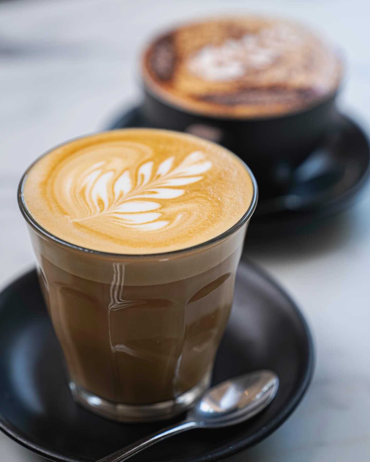 A Close Up of a Cup of Coffee on a Saucer With a Spoon — The Pass Cafe in Byron Bay, NSW