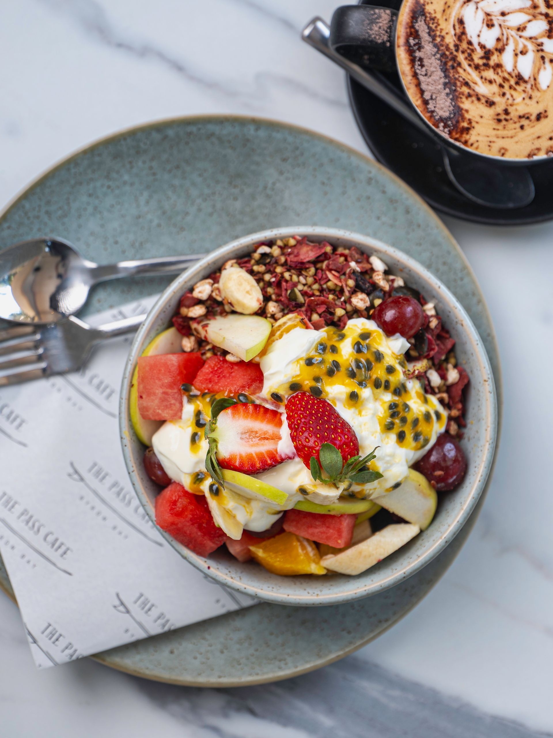 A Bowl of Fruit and Yogurt on a Plate Next to a Cup of Coffee — The Pass Cafe In Byron Bay, NSW