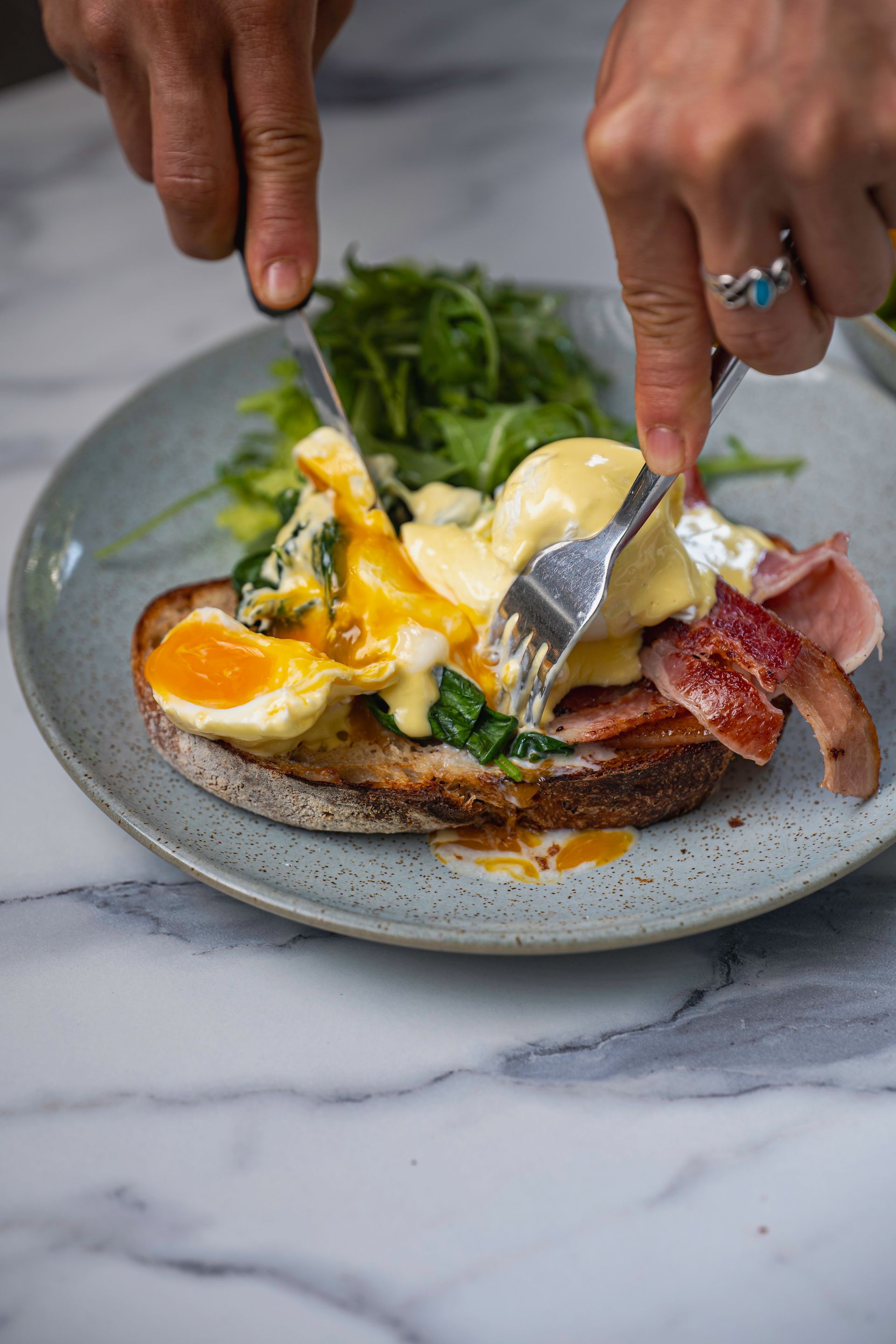 A Person is Cutting an Egg Benedict Sandwich With a Fork — The Pass Cafe In Byron Bay, NSW