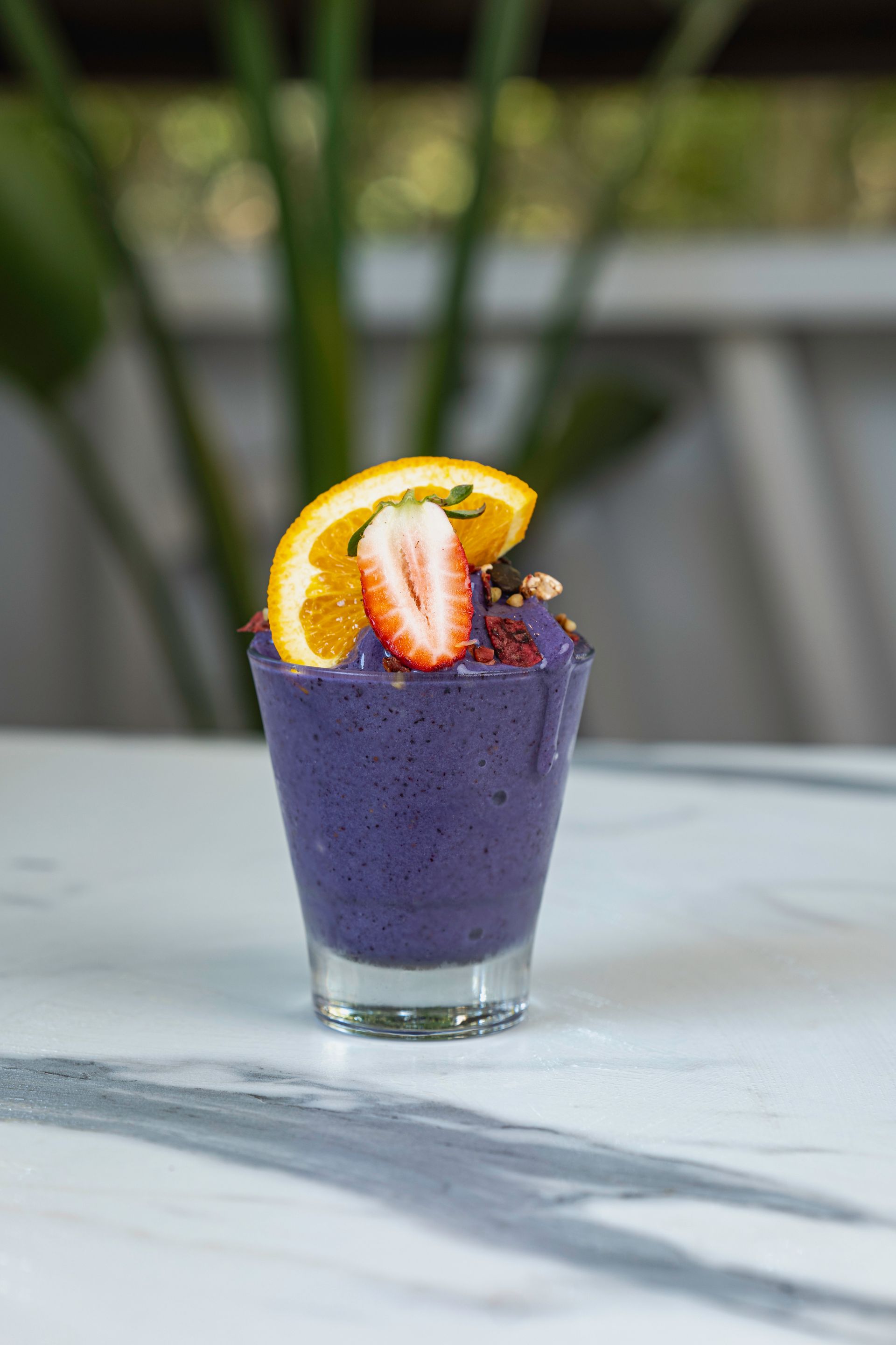 A Purple Smoothie With Strawberries and Orange Slices in a Shot Glass on a Table — The Pass Cafe In Byron Bay, NSW