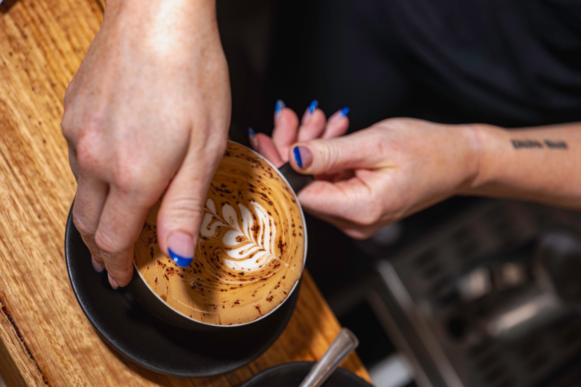 A Woman is Making a Cup of Cappuccino on a Wooden Table — The Pass Cafe In Byron Bay, NSW