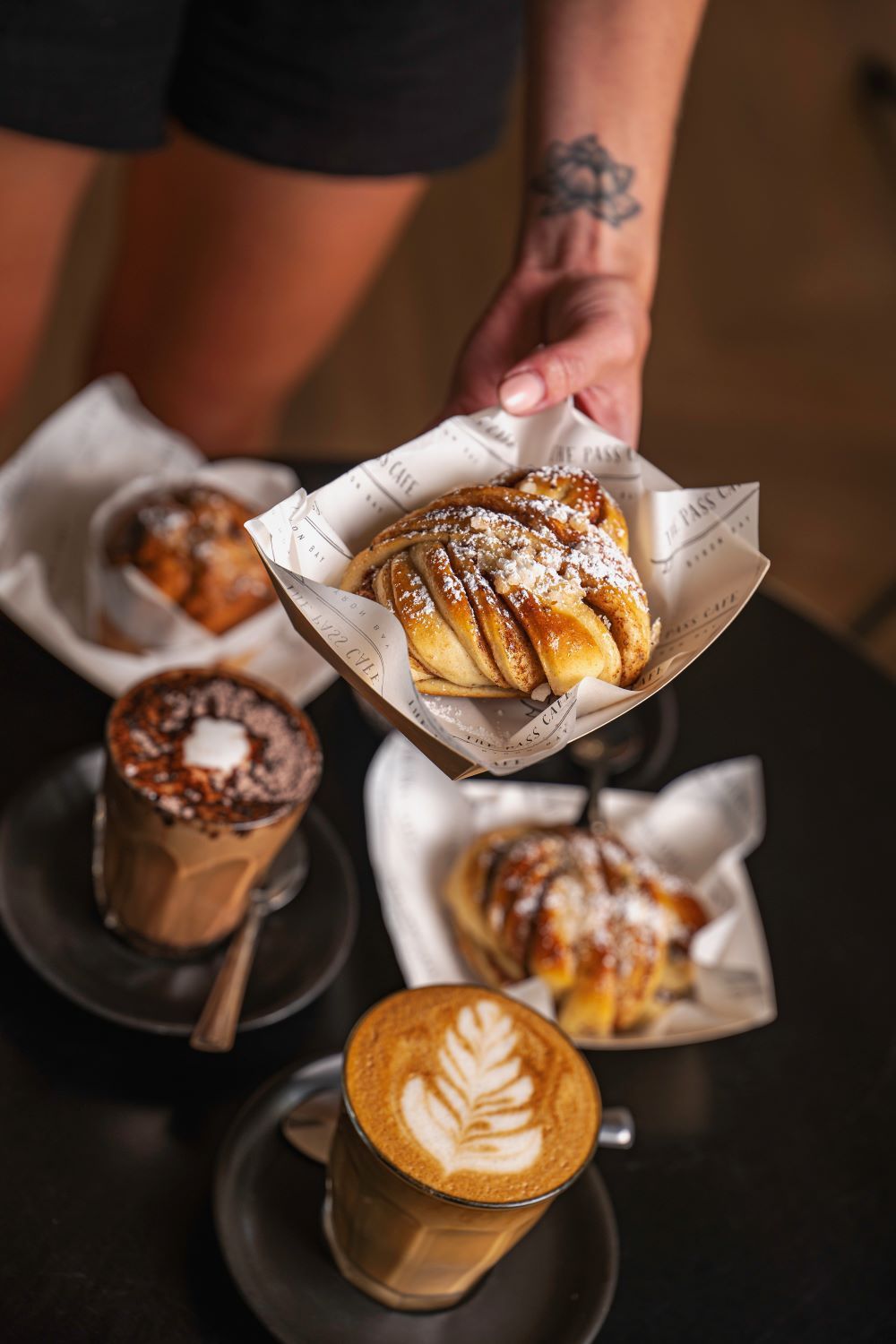 A Person is Holding a Basket of Pastries and a Cup of Coffee — The Pass Cafe in Byron Bay, NSW