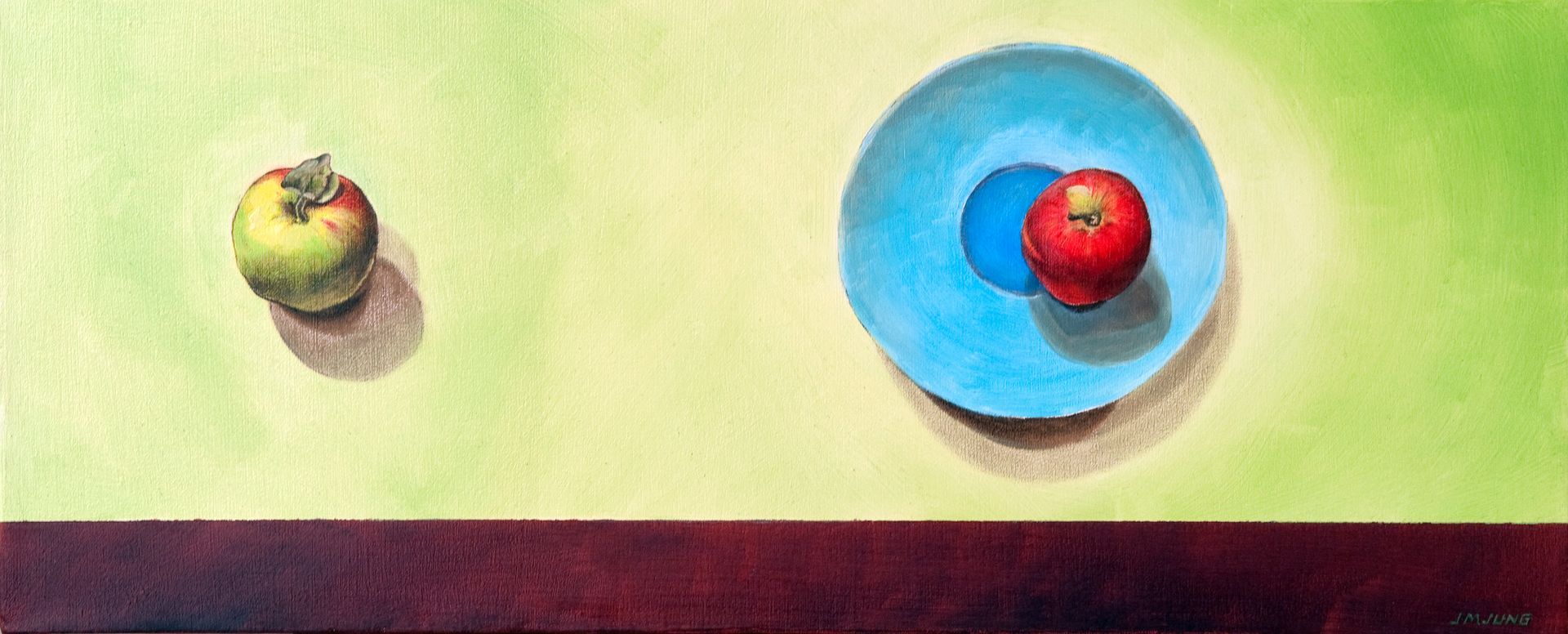 Looking down on one green and red apple and a red apple that is sitting on a blue plate. The background is green and the bottom edge is brown.