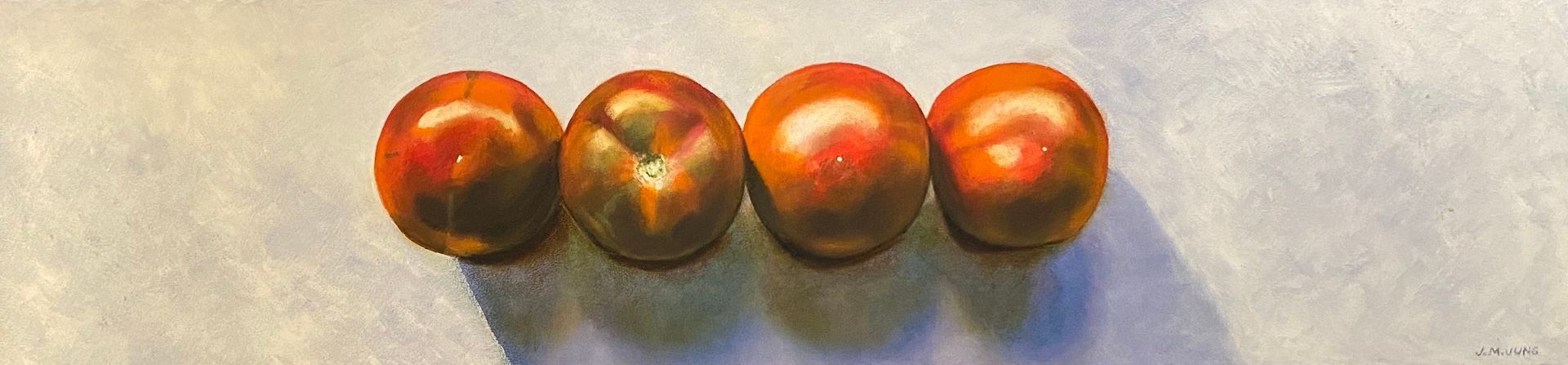 Looking down on four tomatoes against a gray background. Some of the tomatoes are brown to red as it's a brown variety.