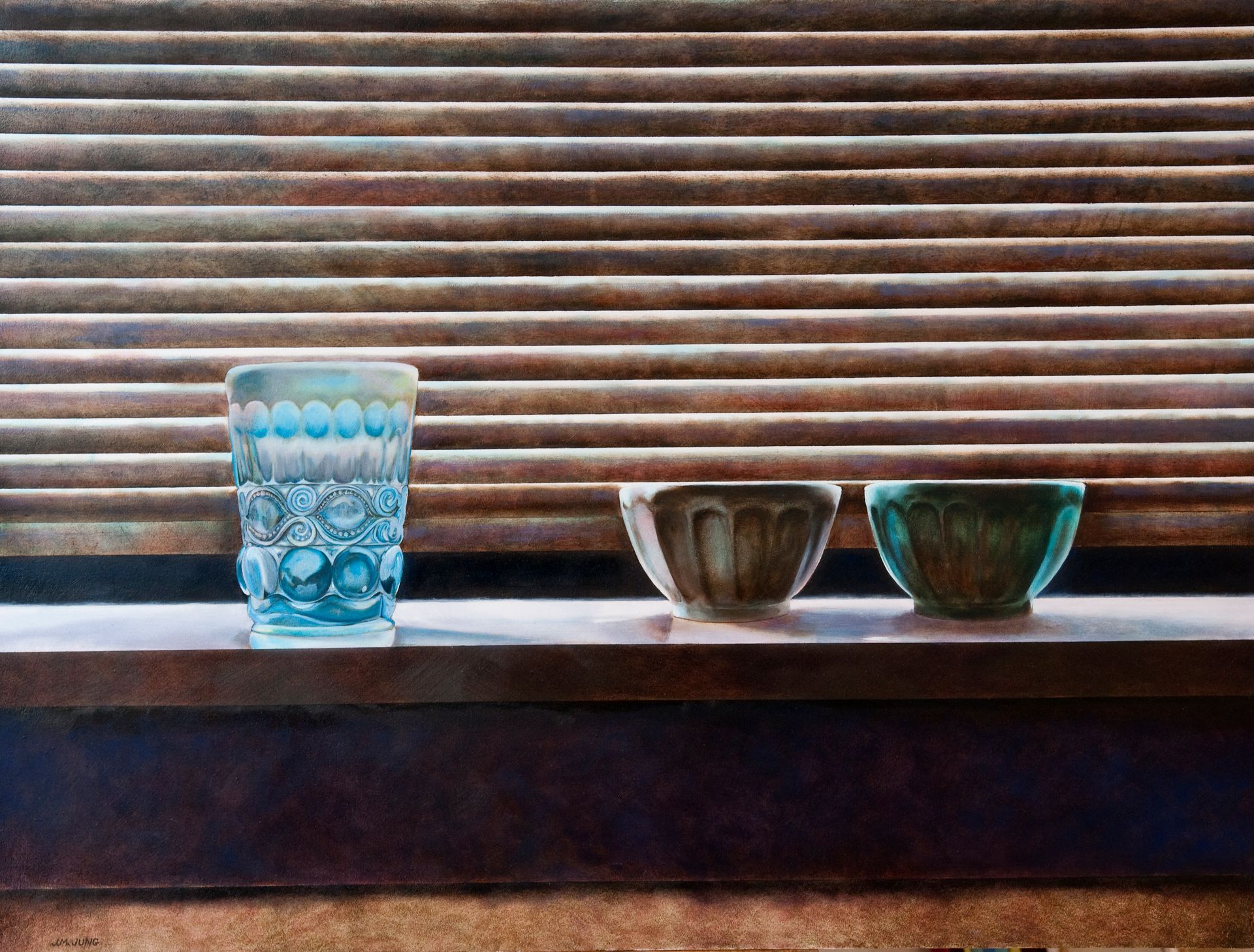 A blue molded glass and two small bowls, one gray, one blue, sitting on a windowsill with light from Venetian blinds falling over them.