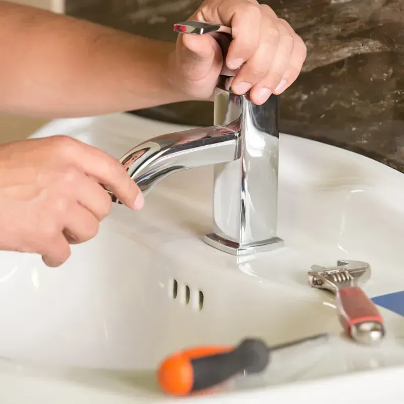 A person is fixing a faucet in a bathroom sink