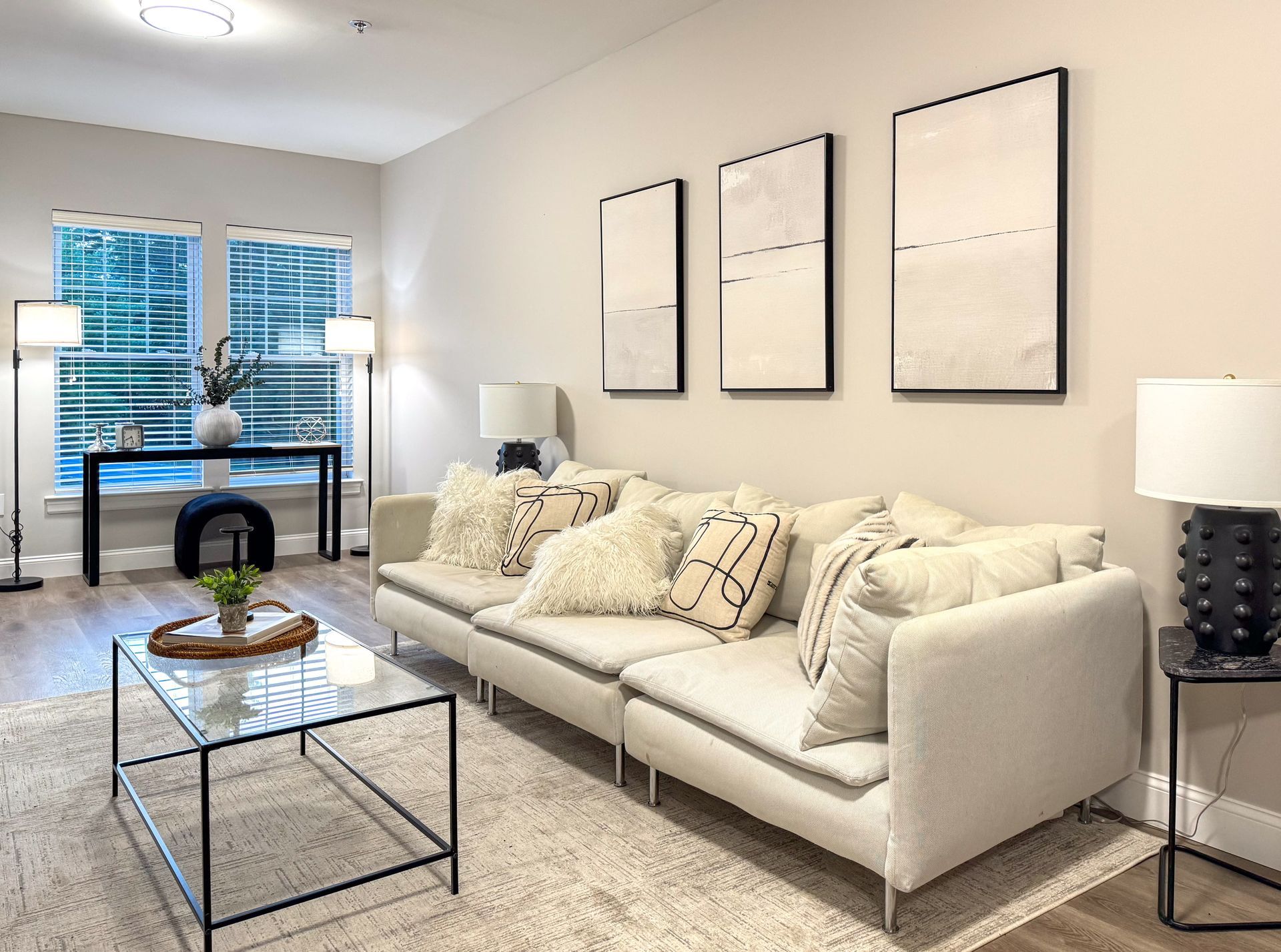Living room with beige sofa, modern art, coffee table, and lamps.