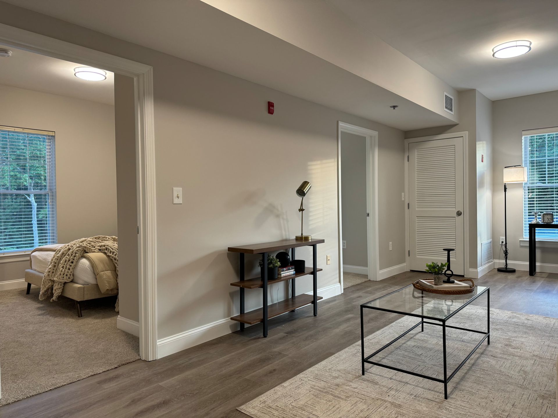 Interior of a modern apartment with a bedroom, living room, and entryway.  Light colors, wood floors.