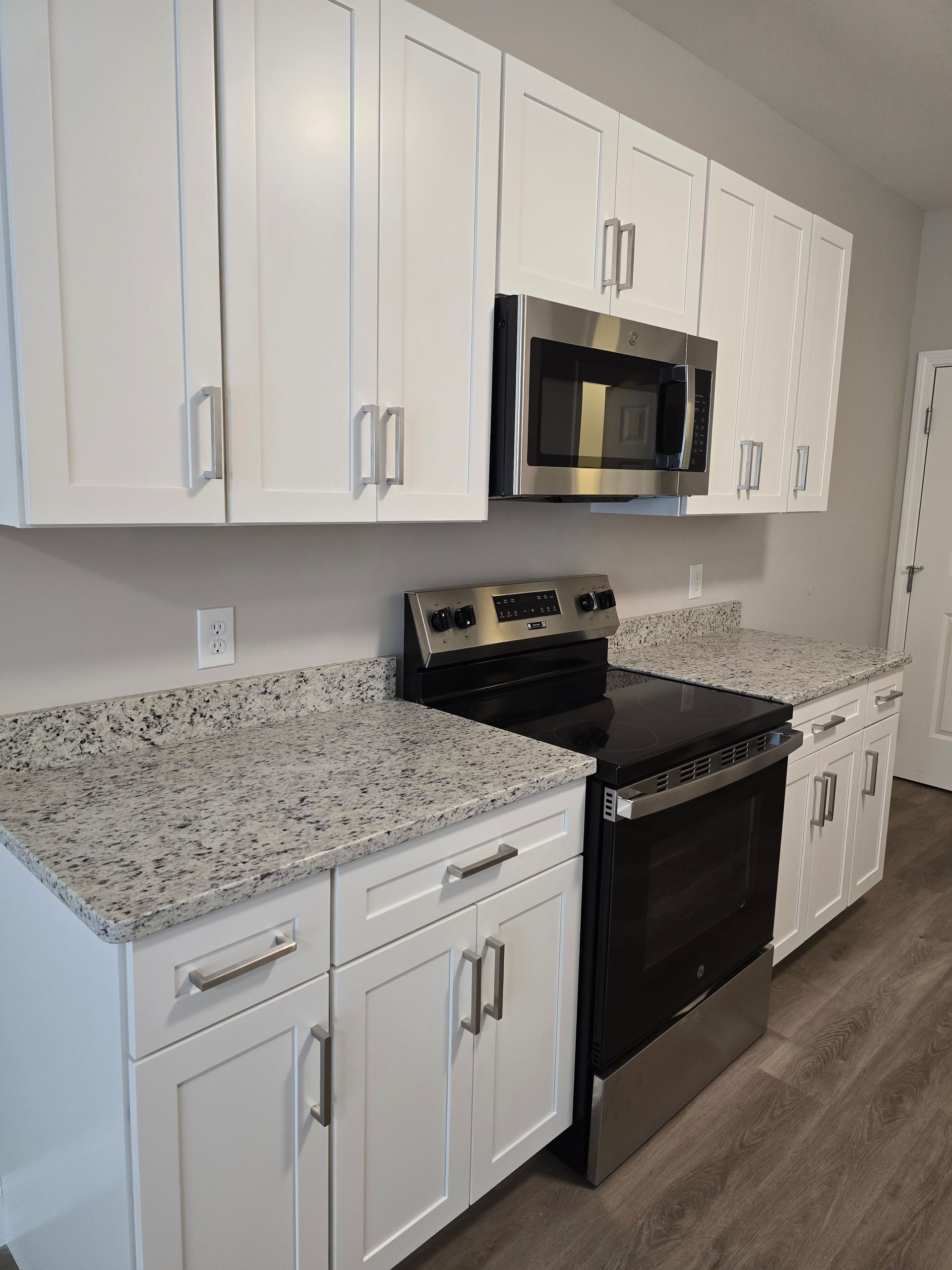 White kitchen cabinets, granite countertops, and stainless steel appliances.