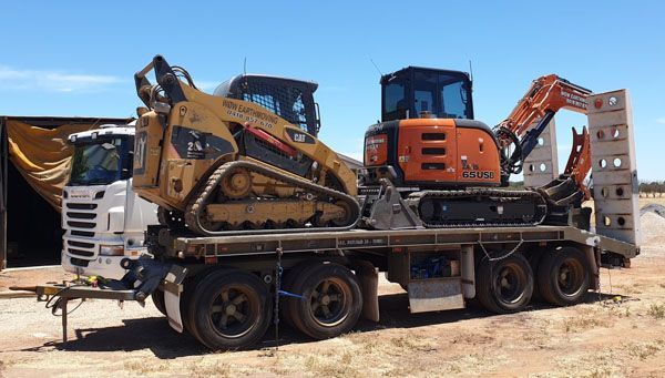 A truck is carrying a bulldozer and an excavator on a trailer.