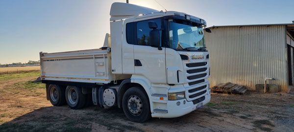 A white dump truck is parked in front of a building.