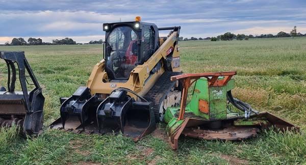 A bulldozer is parked in a grassy field next to a green machine.