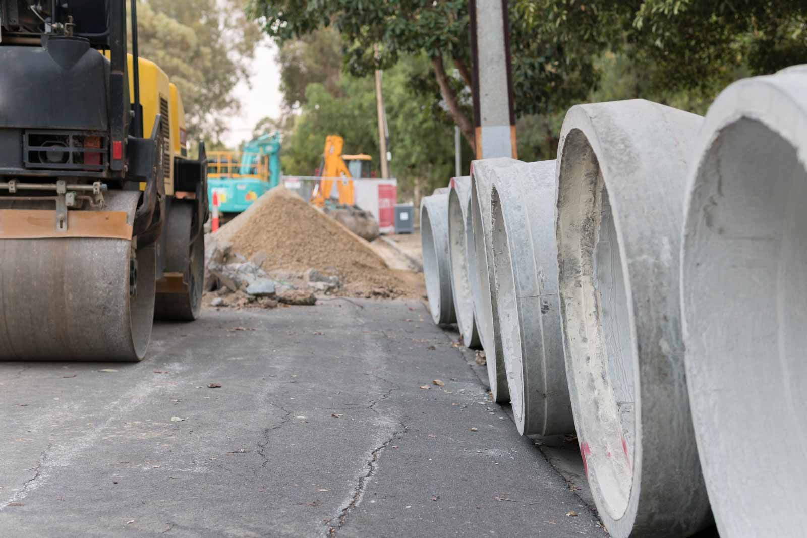 A row of concrete pipes are lined up on the side of a road.